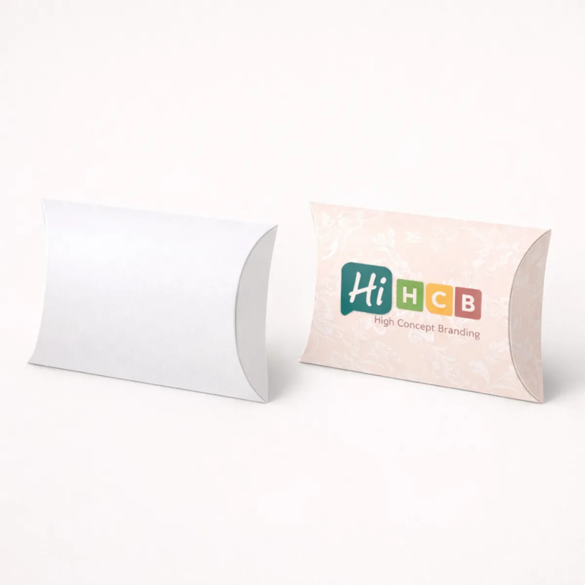 Elegant pillow-shaped gift boxes shown in a minimalist white and a floral pink branded design- class=